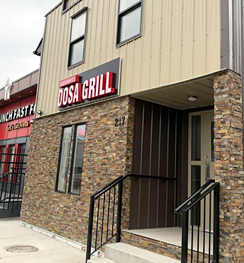 Krishna's Dosa Grill sign above the stone storefront at 217 33rd Street West, Saskatoon