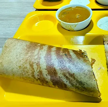 Masala dosa on a yellow tray with sambar