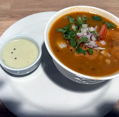 Sambar vada in a bowl of sambar with coconut chutney